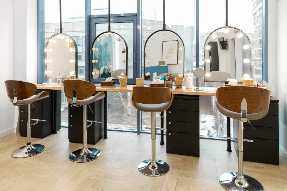Interior luminos al unui salon de coafură modern, cu posturi de lucru elegante și oglinzi profesionale pentru hairstyling.
