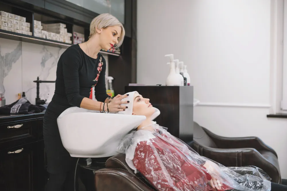 Clientă la spălarea părului într-un salon de înfrumusețare modern, în timpul unui tratament profesional de hair styling.