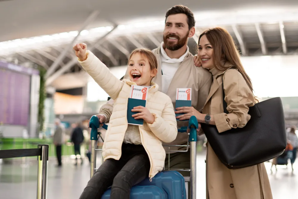 Familie cu copil în aeroport, pregătită de vacanță cu asigurarea de călătorie inclusă