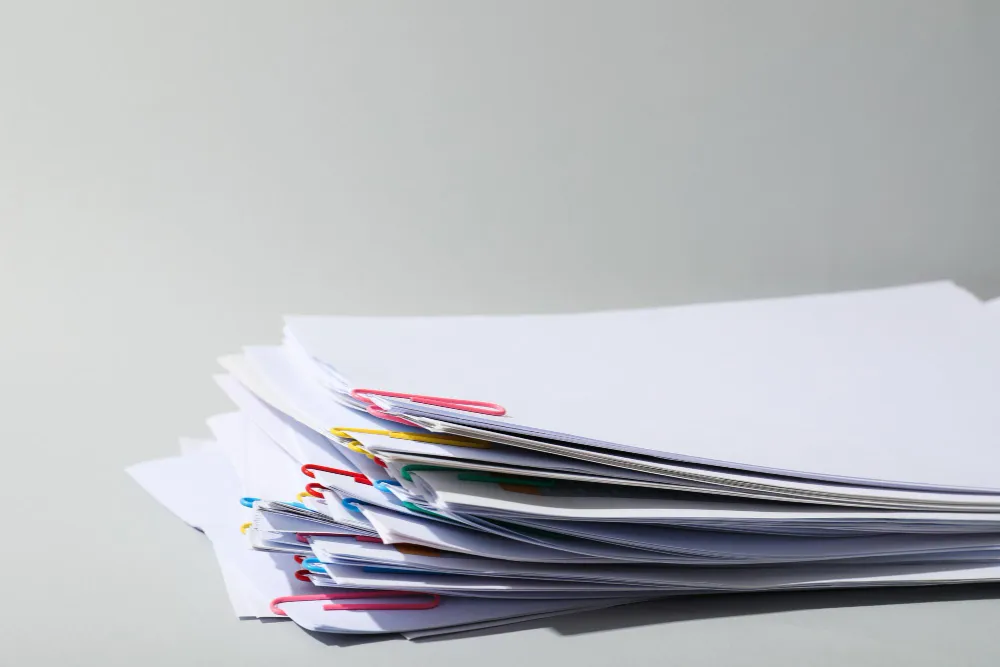 Teanc de documente prinse cu agrafe, pregătite pentru dosarul de mențiuni depus la Registrul Comerțului
