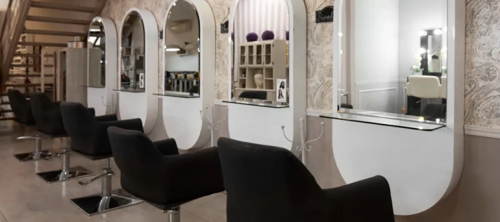 Spațiu elegant de salon de coafură cu scaune profesionale, oglinzi mari și design modern pentru servicii de hairstyling.