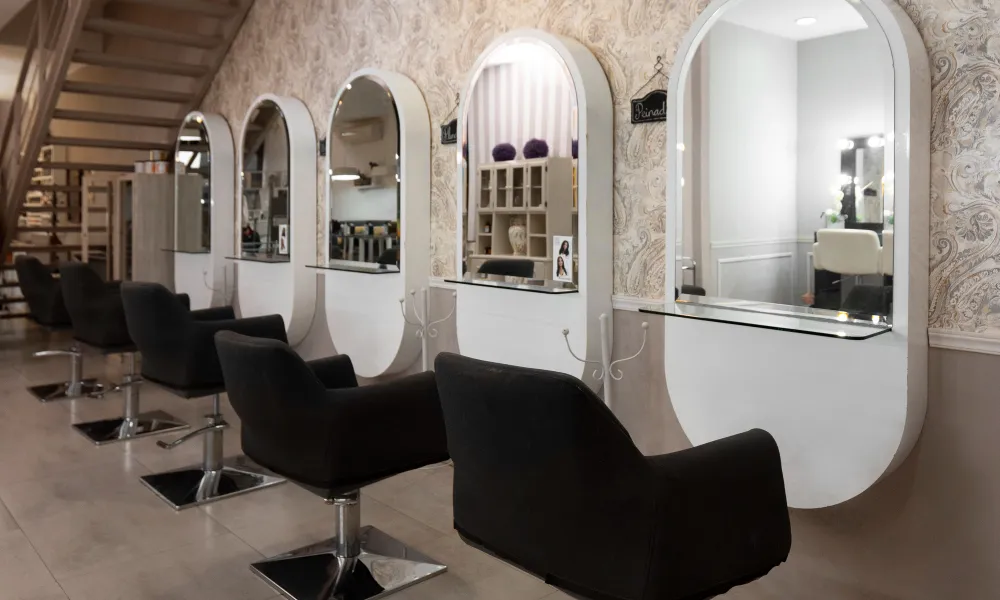 Spațiu elegant de salon de coafură cu scaune profesionale, oglinzi mari și design modern pentru servicii de hairstyling.